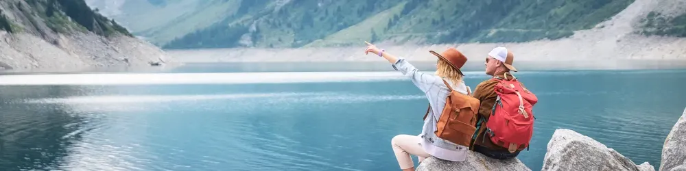 Travelers couple look at the mountain lake. Travel and active life concept with team. Adventure and travel in the mountains region in the Austria